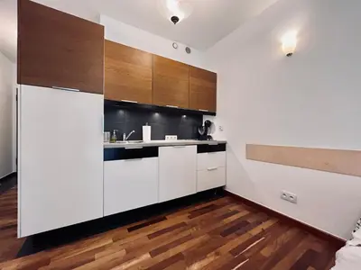 a kitchen with white cabinets and a wooden floor at Central Apart Railway Station in Kraków