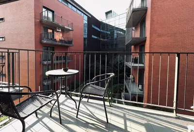 a balcony with two chairs and a table and a building at Central Apart Railway Station in Kraków
