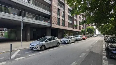 a row of cars parked on the side of a street at Kaszmir Sky Apartment by Vistula River in Kraków