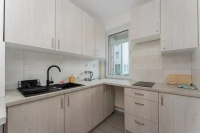 a kitchen with white cabinets and a sink and a window at Konecznego Urban Escape Studio by BookingHost in Kraków