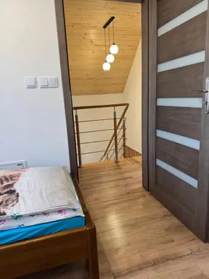 a room with a bed and a wooden door at Agroturystyka Nad Lasem - Domki w górach in Toporzysko