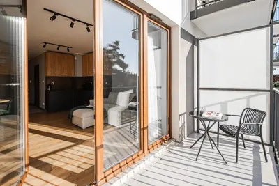 a room with a balcony with glass doors and a table at Apartament Nova Płaszów in Kraków