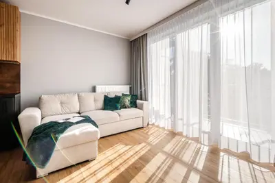 a living room with a couch and a large window at Apartament Nova Płaszów in Kraków