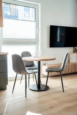 a table and chairs in a living room with a tv at K&M Apartments Tauron Arena, Lema in Kraków