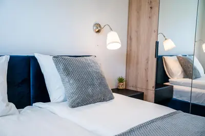 a bedroom with a white bed and a mirror at K&M Apartments Tauron Arena, Lema in Kraków