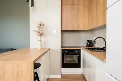 a kitchen with white cabinets and a wooden counter top at Malila Premium Apartments Cracow Rakowicka 437 in Kraków
