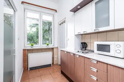 a kitchen with wooden cabinets and a microwave at ShortStayPoland Józefitów C4 in Kraków