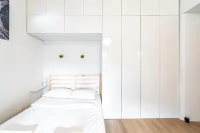 a white bedroom with a bed and white cabinets at ShortStayPoland Józefitów C4 in Kraków