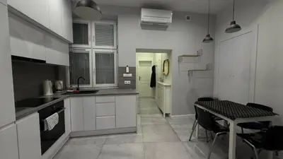 a kitchen with white cabinets and a table with chairs at B37 Kazimierz Apartment in Kraków