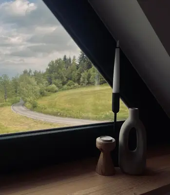 a window with a candle and a vase on a window sill at Łyse Stodoły in Mordarka