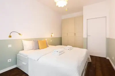 a bedroom with a white bed with two towels on it at NEARTOpl Rakowicka Family apartments in Kraków
