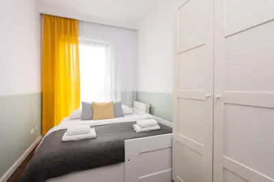 a bedroom with a bed and a yellow curtain at NEARTOpl Rakowicka Family apartments in Kraków