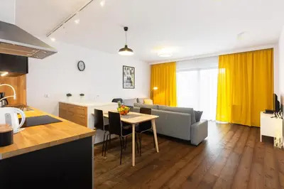 a kitchen and living room with a couch and a table at NEARTOpl Rakowicka Family apartments in Kraków