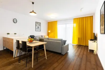 a kitchen and living room with a table and a couch at NEARTOpl Rakowicka Family apartments in Kraków