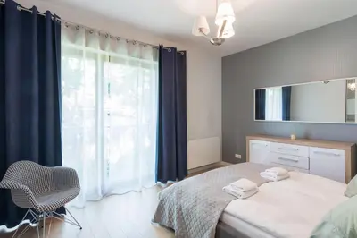 a bedroom with a bed and a large window at NEARTOpl Rakowicka Family apartments in Kraków