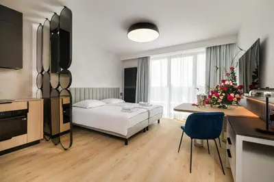 a bedroom with a bed and a table and a kitchen at Wings Plaza in Kraków
