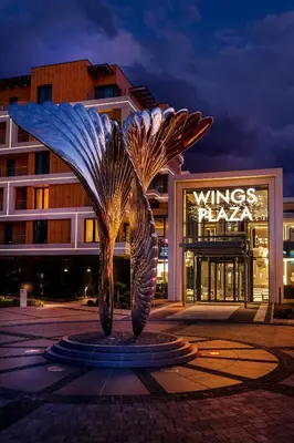 a statue in front of a building at night at Wings Plaza in Kraków
