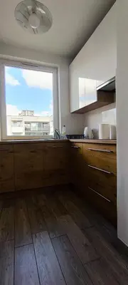 a kitchen with a large window and a kitchen with wooden floors at Apartment Orlińskiego in Kraków