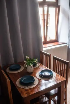 a wooden table with blue plates and a vase on it at Loretas Roses Apartment Krakow Old Town in Kraków