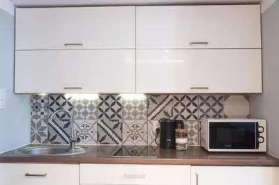 a kitchen with white cabinets and a microwave at Loretas Roses Apartment Krakow Old Town in Kraków