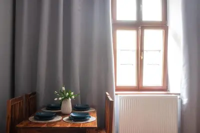 a table with plates and a vase of flowers on it at Loretas Roses Apartment Krakow Old Town in Kraków