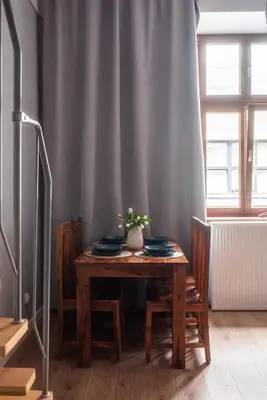 a wooden table with plates and a vase on it at Loretas Roses Apartment Krakow Old Town in Kraków