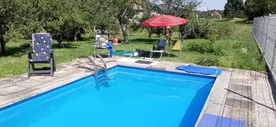 a swimming pool with two chairs and an umbrella at Apartament Szóstka nad Sołą in Czaniec