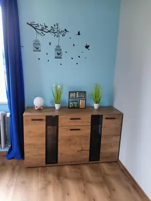a wooden dresser in a room with a blue wall at Apartament Szóstka nad Sołą in Czaniec