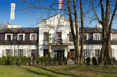a large white house with trees in front of it at Hotel Dwór Kościuszko in Kraków