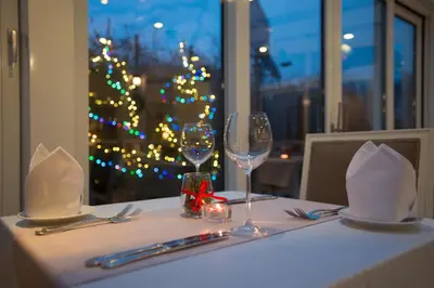 a table with two wine glasses and a christmas tree at Hotel Dwór Kościuszko in Kraków