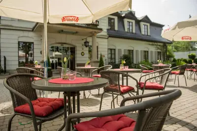 an outdoor patio with tables and chairs with umbrellas at Hotel Dwór Kościuszko in Kraków