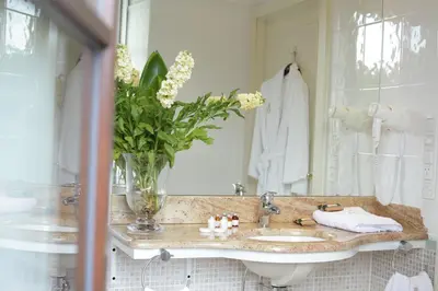a bathroom with a sink and a vase of flowers at Hotel Dwór Kościuszko in Kraków