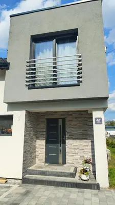 a gray house with a balcony and a door at Domek Liliowe Marzenie in Chrzanów