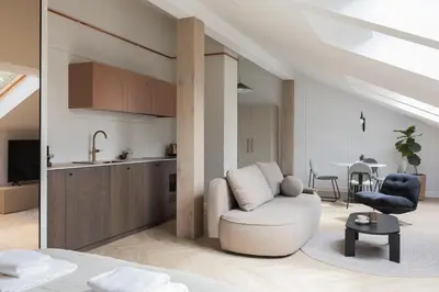 a living room with a chair and a kitchen at Venus Apartment in Kraków
