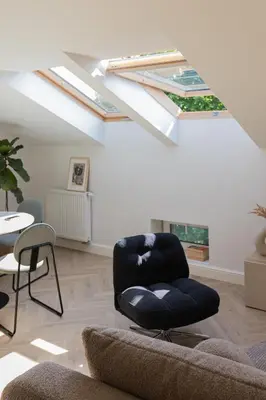 a black chair in a living room with skylights at Venus Apartment in Kraków