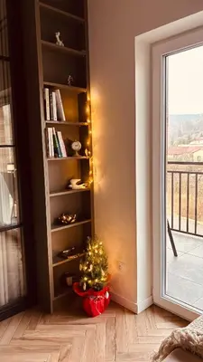 a christmas tree in a room with a book shelf at Nowoczesny apartament w Makowie Podhalańskim in Maków Podhalański