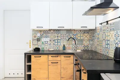 a kitchen with white cabinets and a black counter top at Park Krakowski Homely Studio with Garden by BookingHost in Kraków
