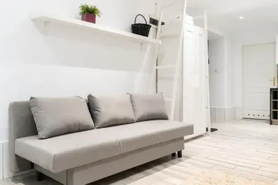 a bedroom with white walls and a bed with white pillows at Park Krakowski Homely Studio with Garden by BookingHost in Kraków