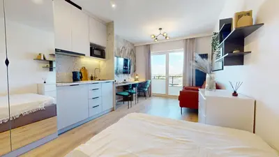 a bedroom with a bed and a kitchen with a desk at Apartamenty na Pana Tadeusza in Kraków