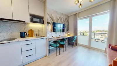 a kitchen with white cabinets and a bar with stools at Apartamenty na Pana Tadeusza in Kraków