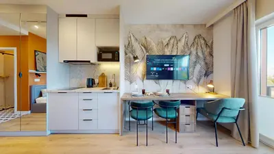 a kitchen with a table with chairs and a tv on a wall at Apartamenty na Pana Tadeusza in Kraków