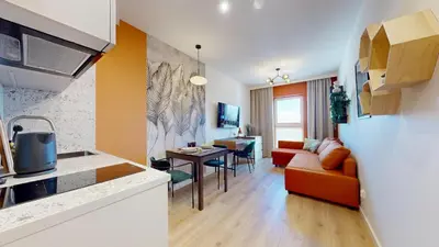 a kitchen and living room with a couch and a table at Apartamenty na Pana Tadeusza in Kraków