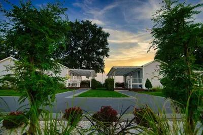 a large white house with trees and a driveway at Skandynawia Przystań & Family Resort in Zator
