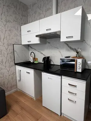 a kitchen with white cabinets and a brick wall at Apart HOSTEL - KrakHouse in Kraków