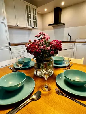 a table with plates and glasses and a vase of flowers at Apartament Gucio in Zator