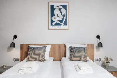 a bedroom with two beds and a picture on the wall at Monika Apartments by Upstairs in Kraków