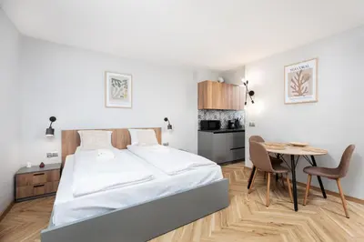 a bedroom with a bed and a table and a kitchen at Monika Apartments by Upstairs in Kraków