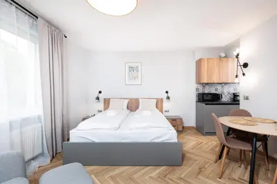 a white bedroom with a bed and a table at Monika Apartments by Upstairs in Kraków