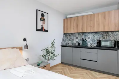 a bedroom with a bed and a kitchen at Monika Apartments by Upstairs in Kraków