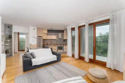 a living room with a couch and a kitchen at Wilga Park Homely Apartment by BookingHost in Kraków